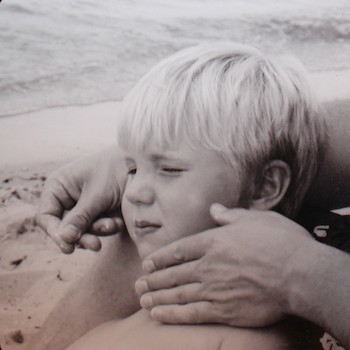 Shawnelle's son Grant as a young boy, being caressed by his father's hands.
